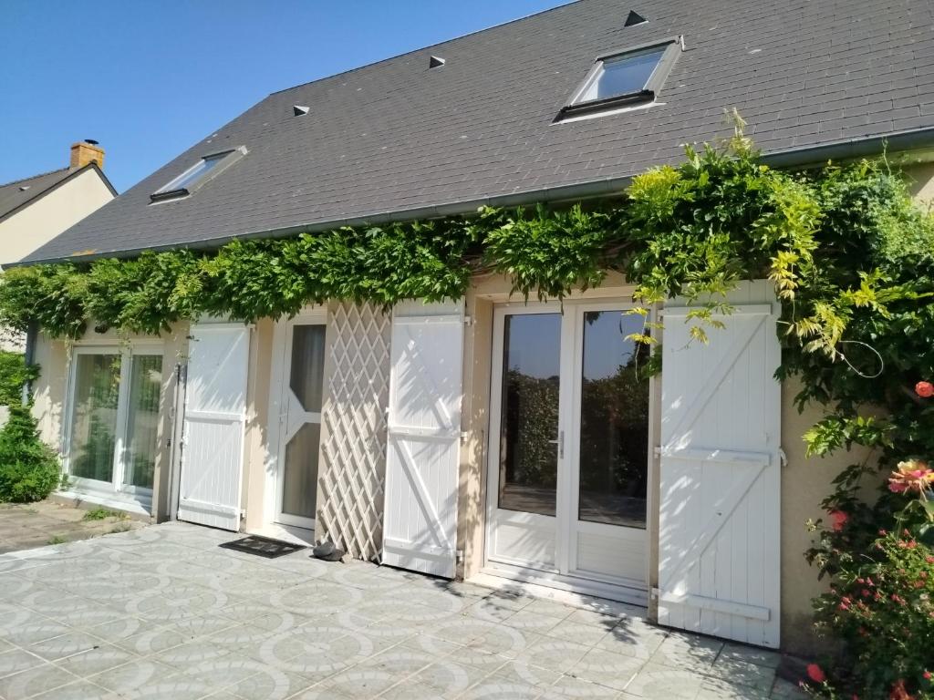 a pair of white garage doors with vines at Gîte les coccinelles en Baie du Mont St Michel in Dragey