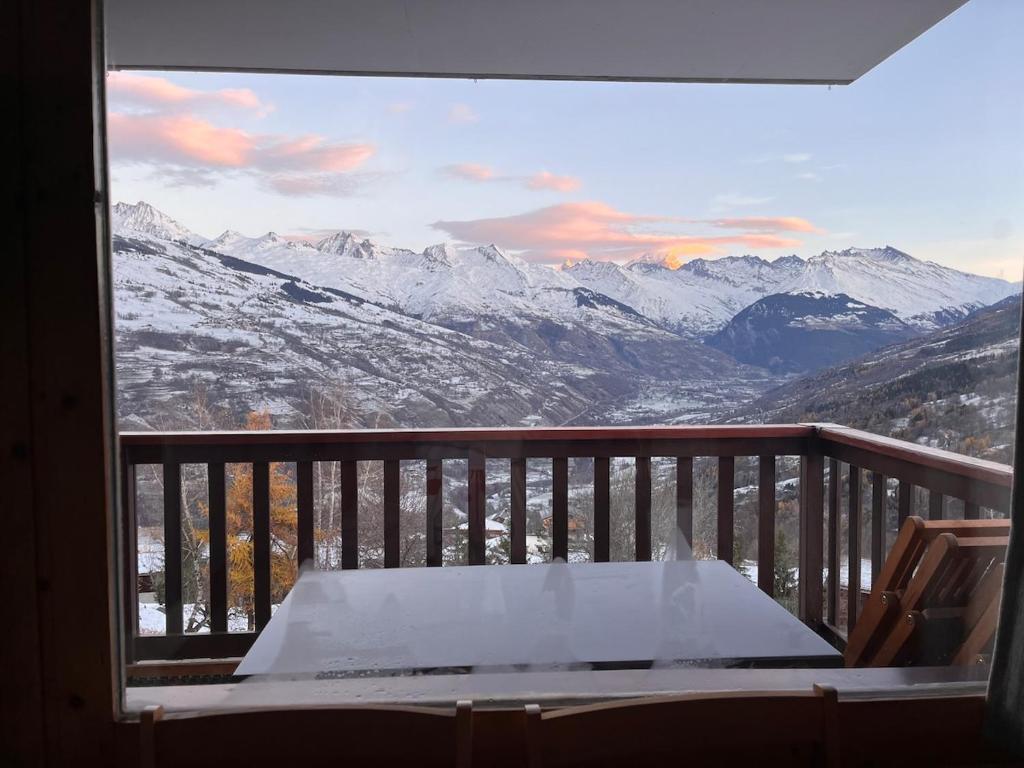 un balcon avec une table et une vue sur les montagnes dans l'établissement Appartement Montchavin - accès direct piscine et remontées mécaniques, à La Plagne Tarentaise