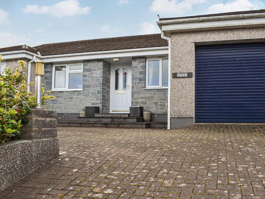 a house with a blue garage door on a brick driveway at Heather Cottage in Saint Erth