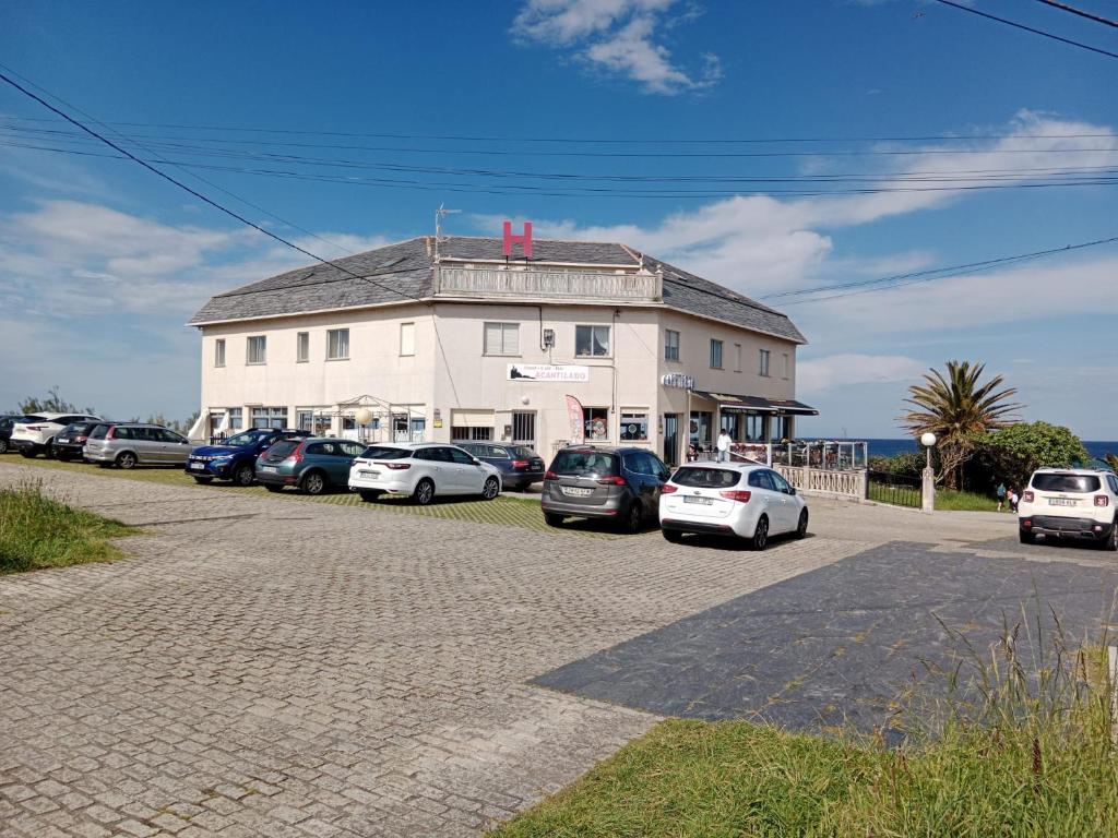 a large white building with cars parked in front of it at Hostal Acantilado in Villadaíde