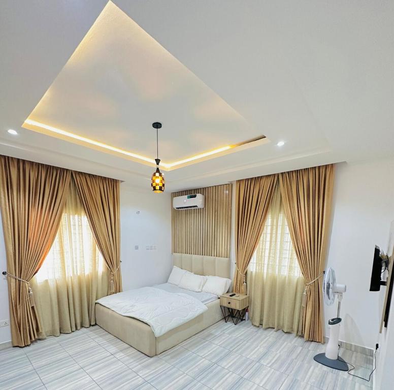 a bedroom with a large bed and two windows at SolarisApartment in Abuja