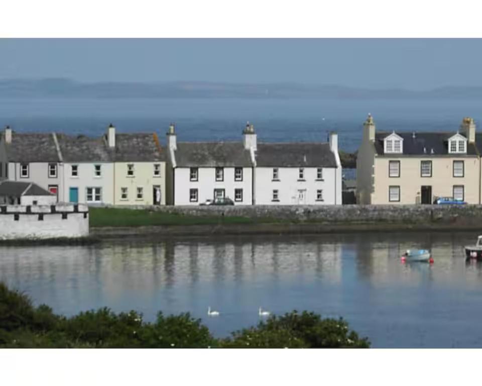 un groupe de maisons blanches au bord d'une étendue d'eau dans l'établissement Pass the Keys Gorgeous 3 BR Cottage with Outstanding Sea Views, à Isle of Whithorn