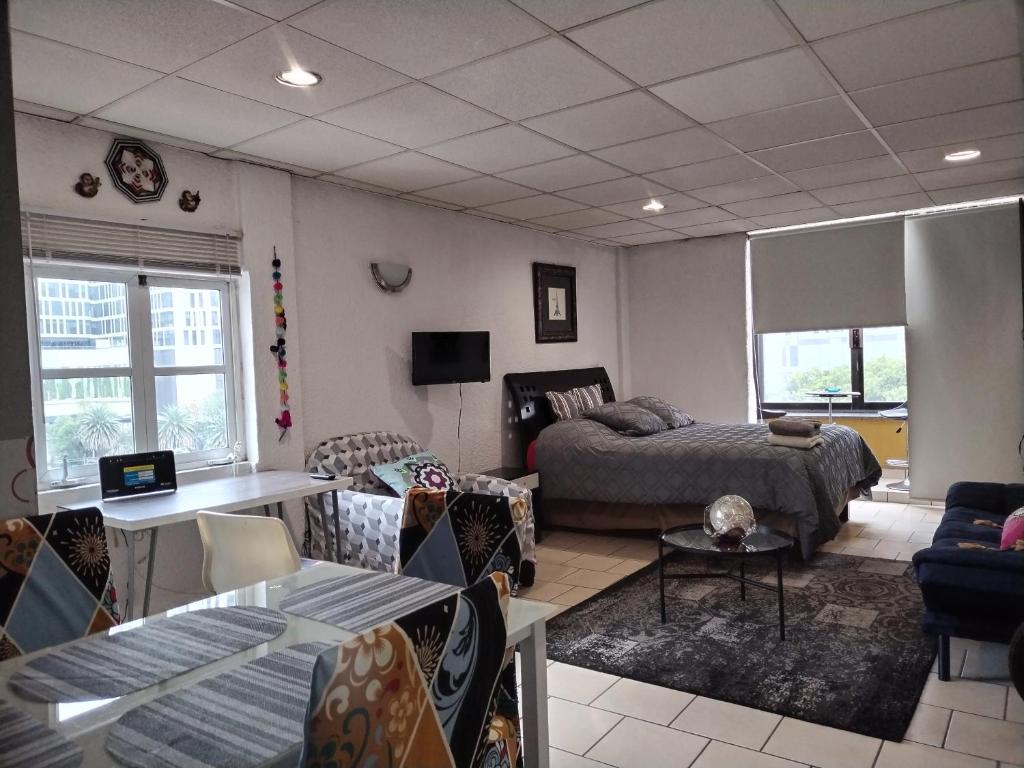 ein Wohnzimmer mit einem Bett und einer Couch in der Unterkunft Suite Reforma Ahuehuete in Mexiko-Stadt