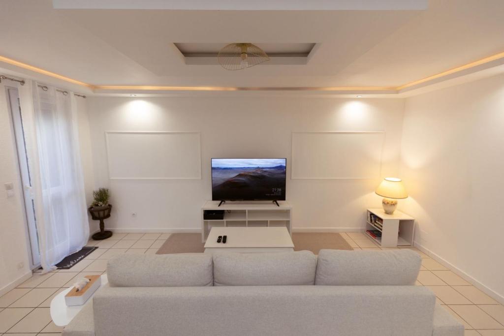 a living room with a couch and a flat screen tv at Grande maison des Compagnons in Val de Reuil