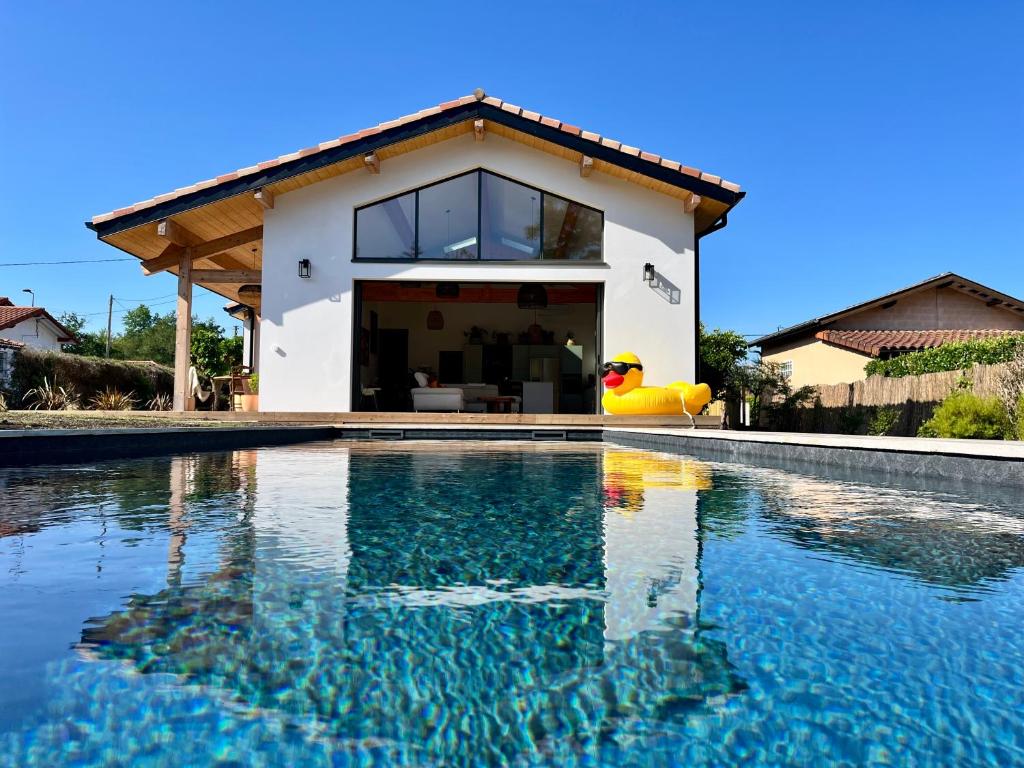 une maison avec une piscine devant une maison dans l'établissement Villa Christelle, à Soustons