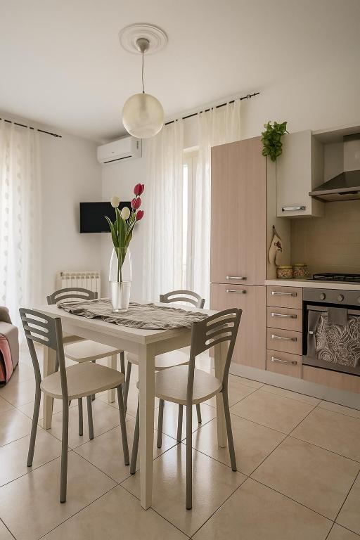 a dining room table with chairs and a vase with flowers at Casa Stella in Crotone