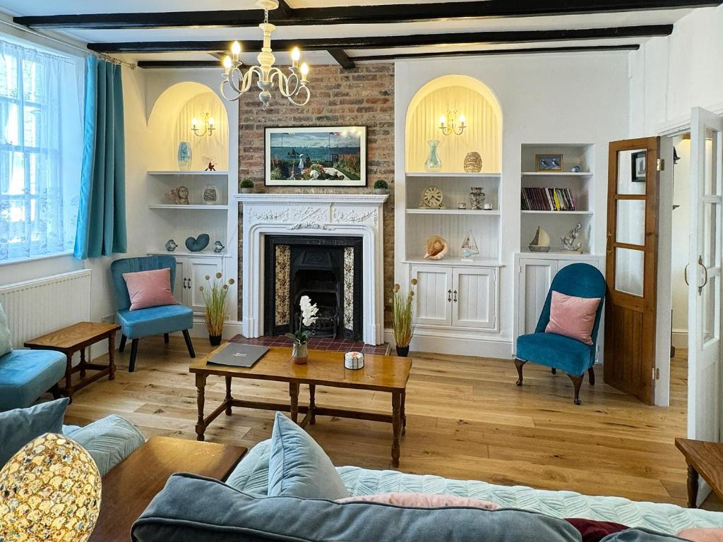 a living room with a fireplace and blue chairs at The Anchor in Scarborough