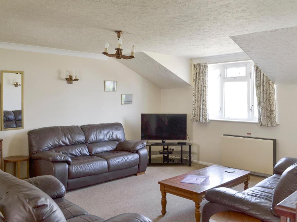 ein Wohnzimmer mit Ledercouch und Fernseher in der Unterkunft Sea Haven - Uk44499 in Hope-Cove