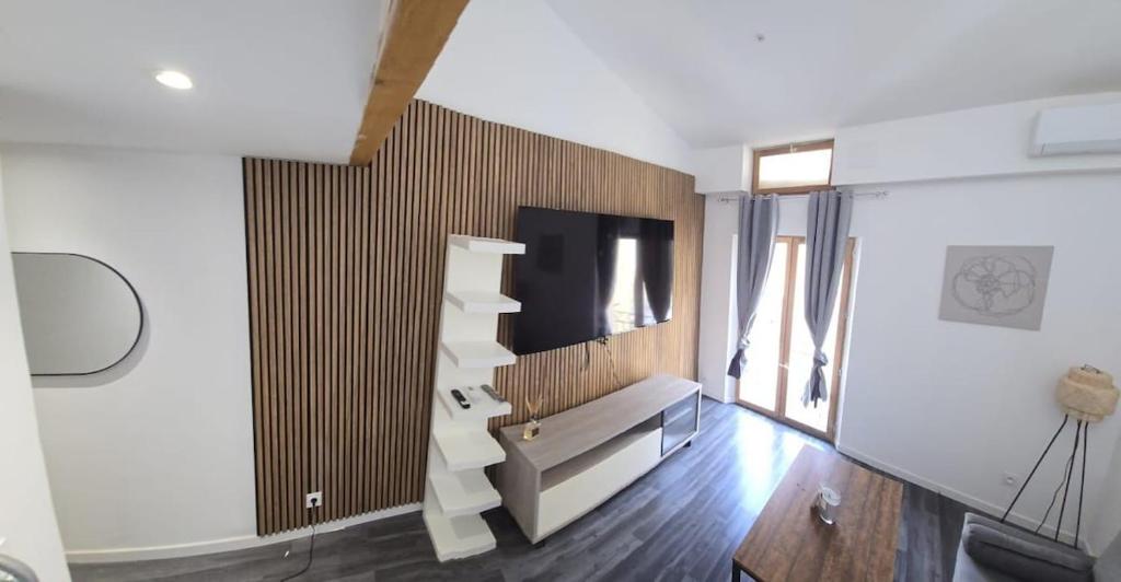 un salon avec une télévision sur un mur dans l'établissement Le Cocon de Clermont, à Clermont-lʼHérault