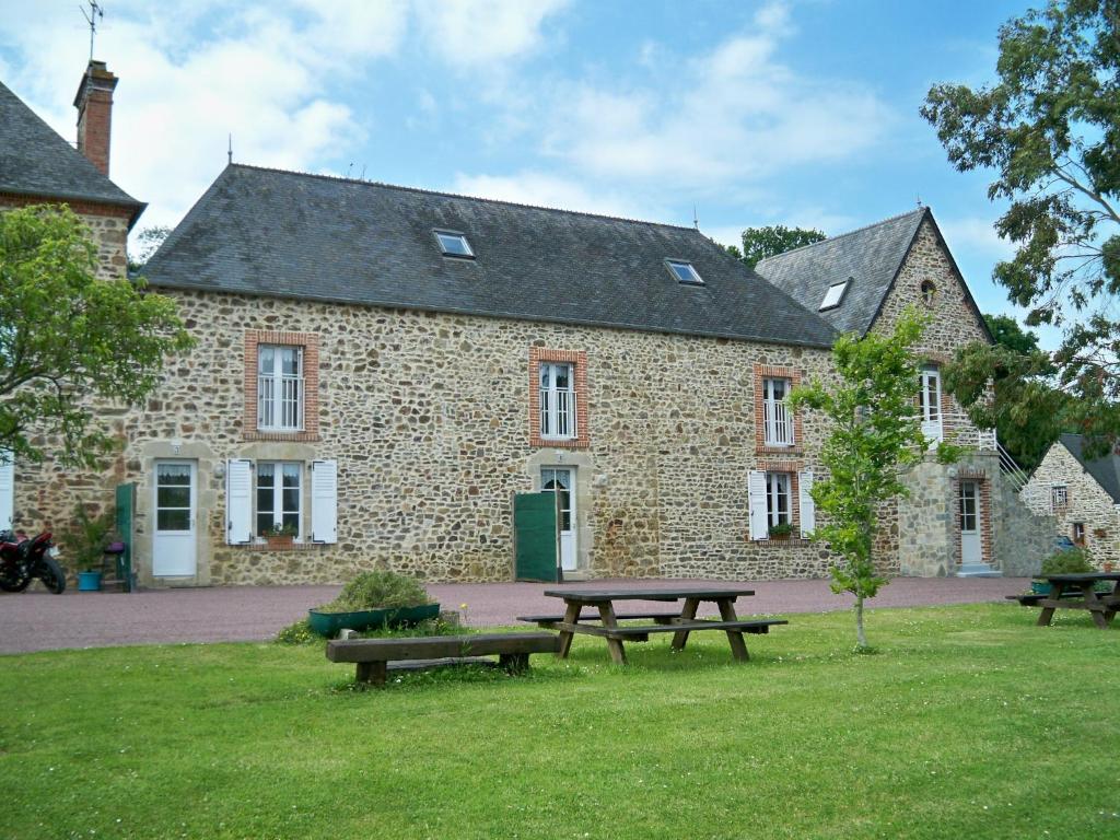 - un bâtiment en pierre avec une table de pique-nique devant dans l'établissement Gîte le Lasnier, à Crasville