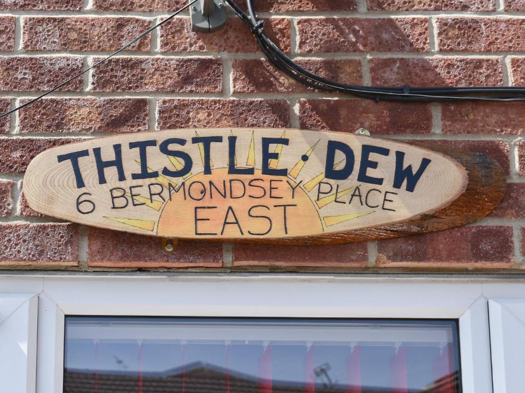 a sign on a brick wall above a door at Thistle Dew in Great Yarmouth