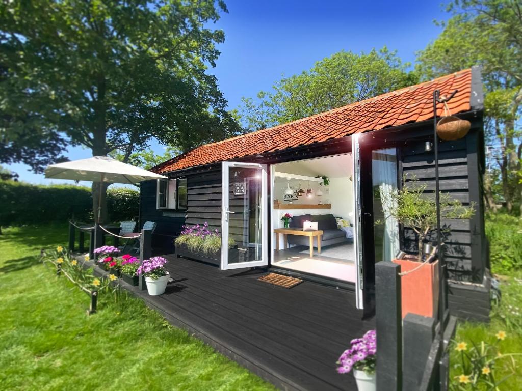a tiny house with a deck and an open door at The Little Barn in Hoxne