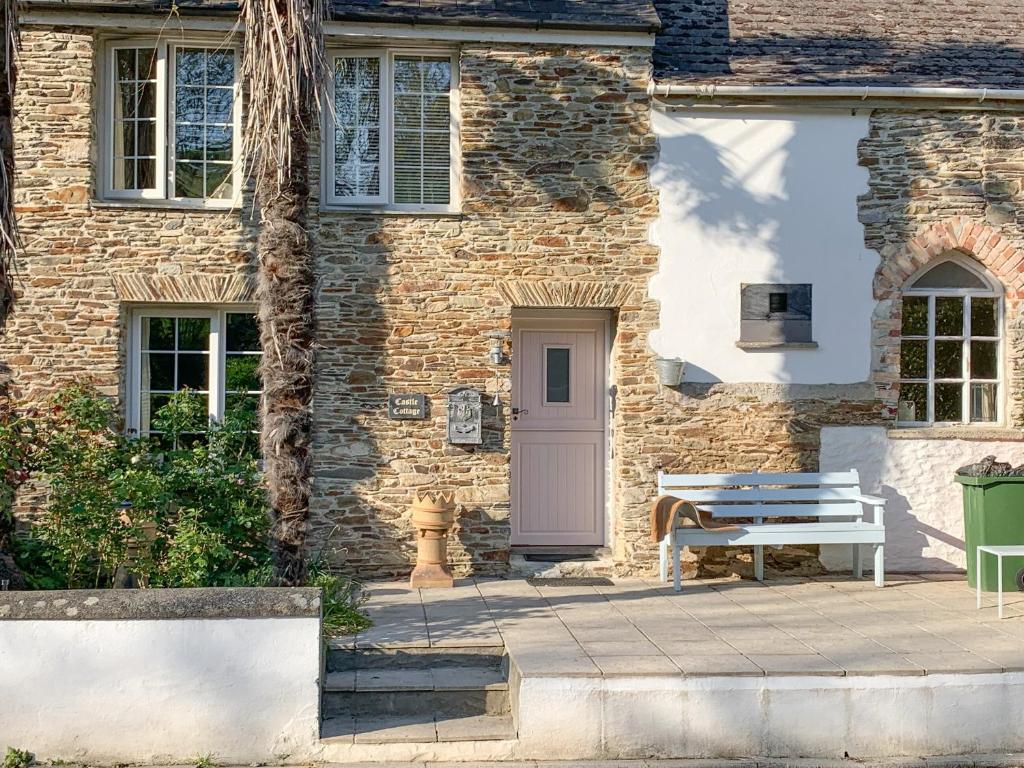 a brick house with a bench and a door at Castle Cottage in Ruan Lanihorne
