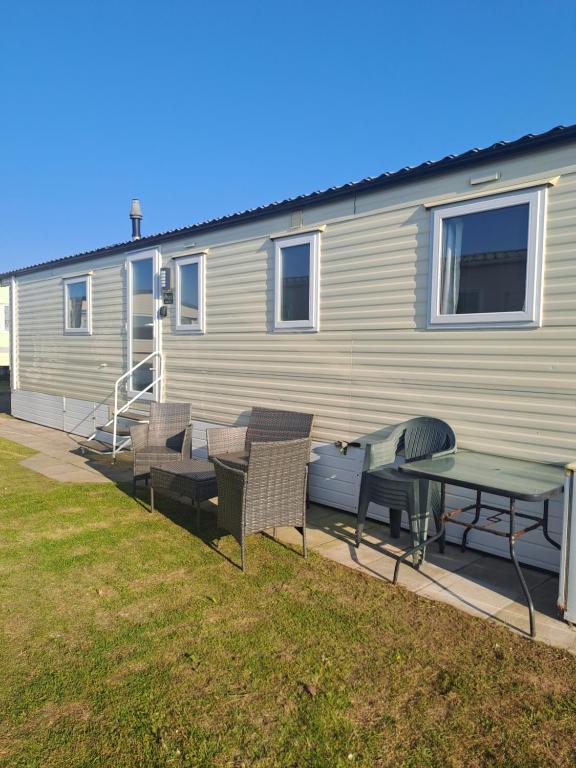 a house with a patio with a table and chairs at Trecco Bay Cwtch Caravan in Newton