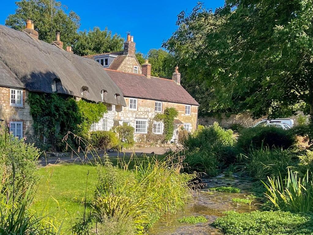 an old stone house with a thatched roof at Winkle Cottage in Calbourne