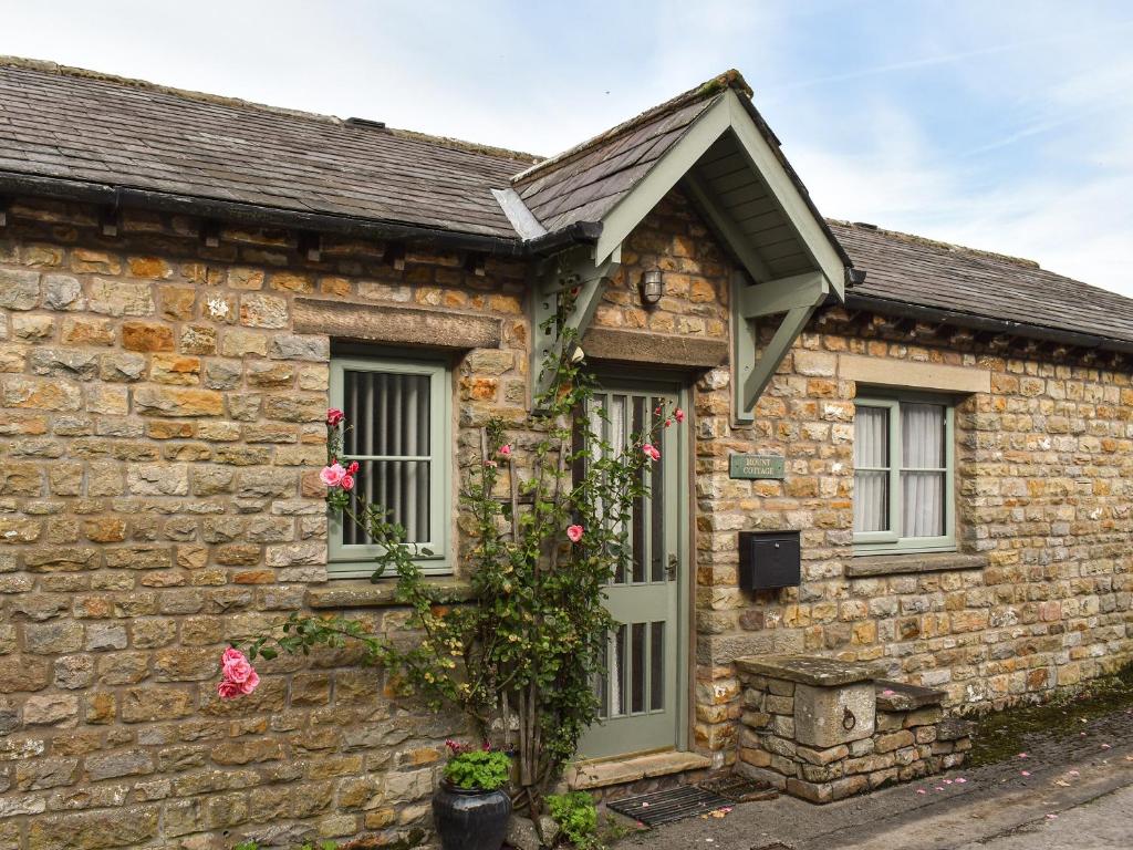 une maison en pierre avec des roses sur son côté dans l'établissement Mount Cottage, à Wennington