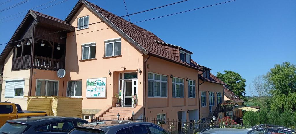 a building with cars parked in front of it at Tabán Vendégház in Balatonlelle