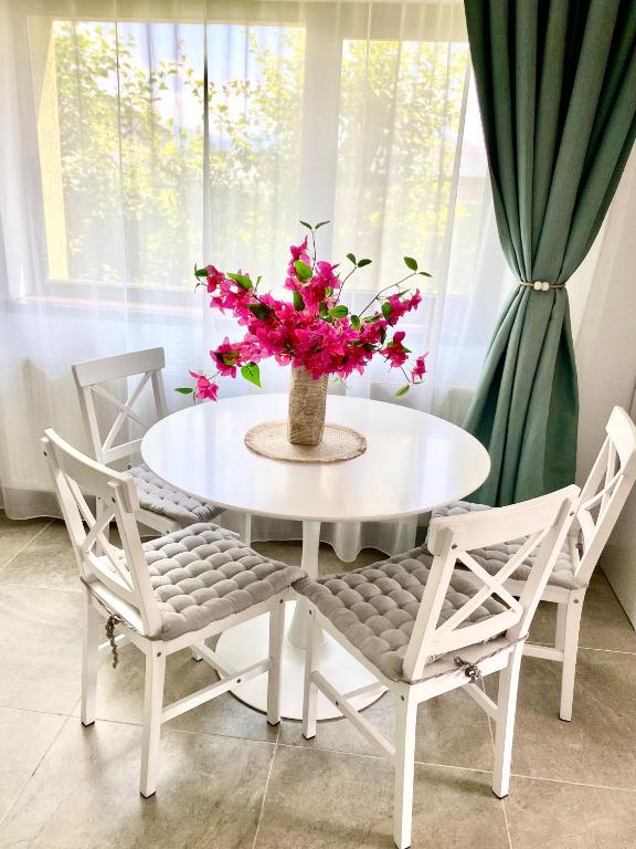 a white table and chairs with a vase with pink flowers at Vila Suveranii in Braşov