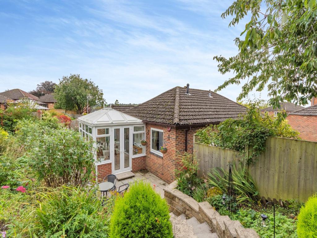 a brick house with a conservatory in a garden at Cherry Tree Corner in Ashbourne