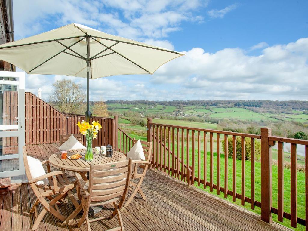 a wooden deck with a table with an umbrella at Valley View - Uk43268 in Luppitt