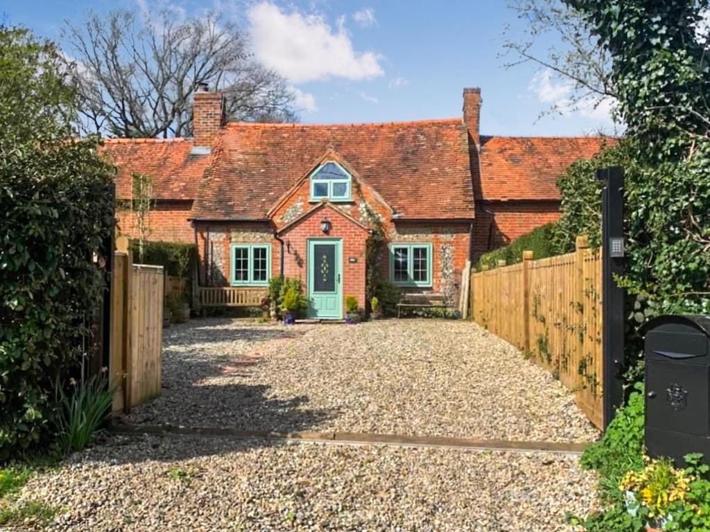 a home with a wooden fence and a driveway at Burwood Cottage in Rotherfield Peppard
