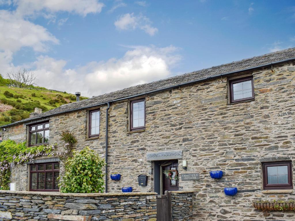 une maison en pierre avec un mur en pierre dans l'établissement The Studio At Malt Kiln Cottage, à Grizebeck