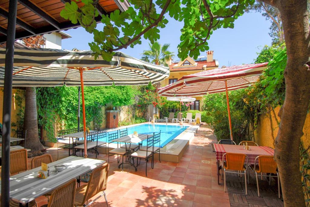 een zwembad met tafels, stoelen en parasols bij Villa Danlin Hotel in Göcek