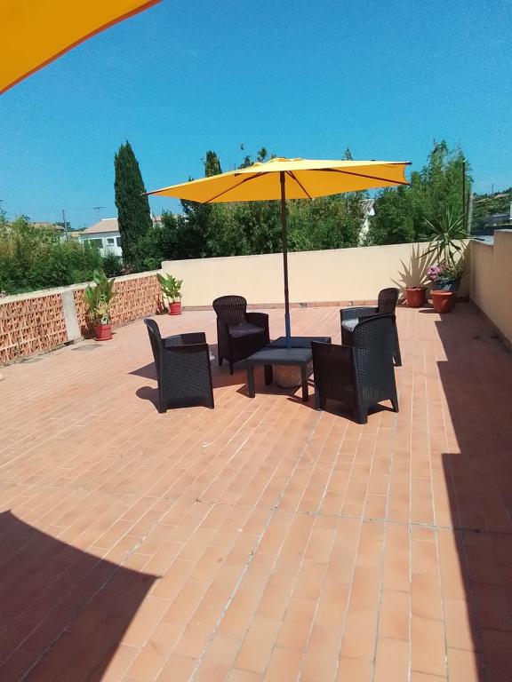 un patio avec une table, des chaises et un parasol dans l'établissement 1 er étage, à Lunel-Viel