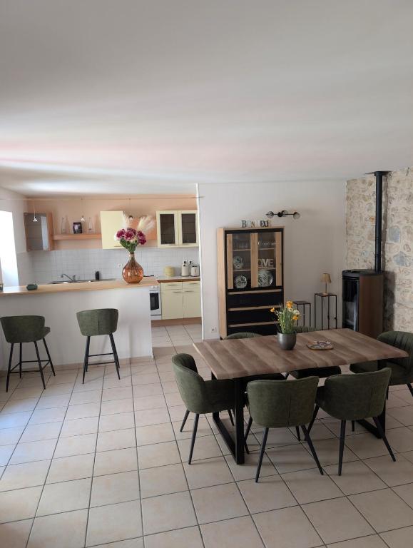 une cuisine et une salle à manger avec une table et des chaises en bois dans l'établissement Évasion vigneronne, jolie maison de village en pierre, à Vallon-Pont-dʼArc