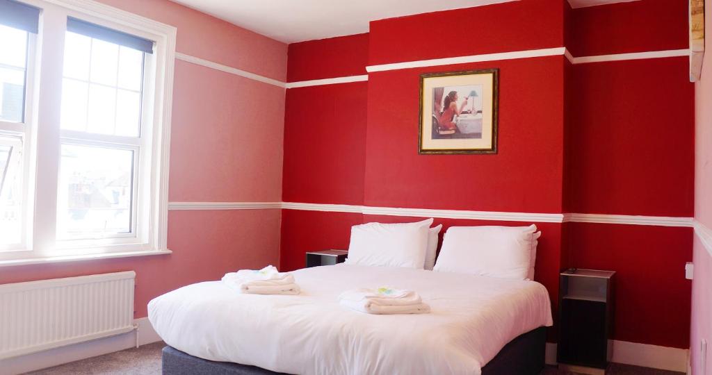 a red bedroom with a bed with towels on it at The Loriston in Eastbourne