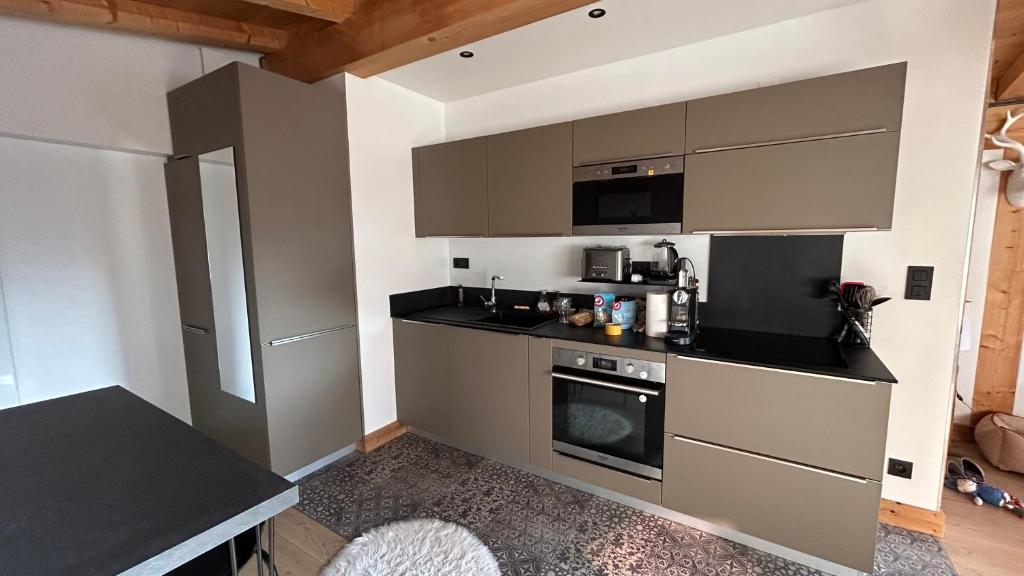 a kitchen with gray cabinets and a black counter top at Roof top Moutain view direct access Morzine Avoriaz in Montriond