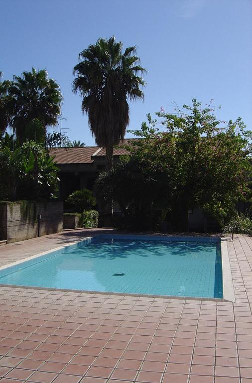 niebieski basen z palmami i dom w obiekcie Calipso Bed&Breakfast w Katanii