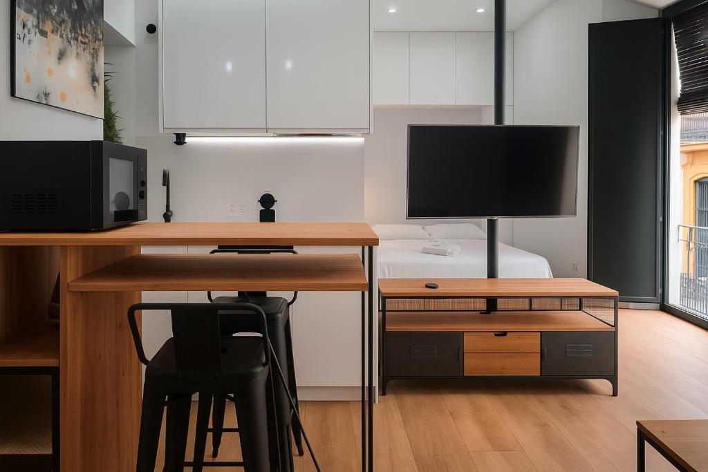 ein Wohnzimmer mit einem Schreibtisch, einem TV und einem Computer in der Unterkunft Tourist House Francos in Sevilla