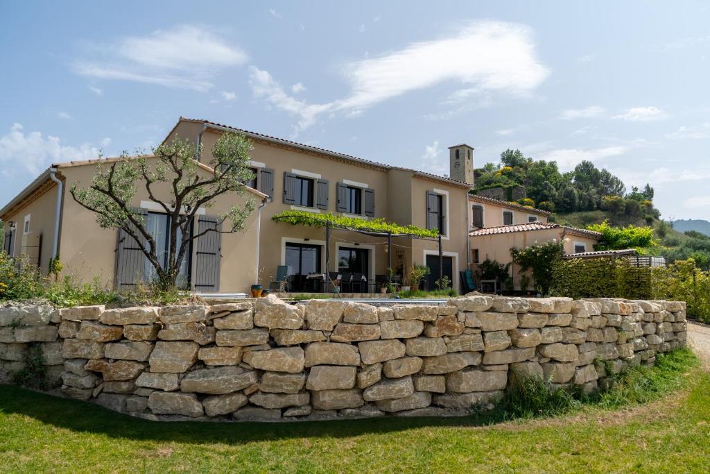 un mur en pierre devant une maison dans l'établissement VILLA en Drome Provencale, à Piégon