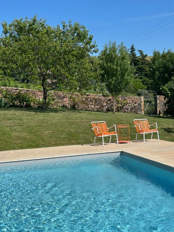 two chairs sitting next to a swimming pool at Chambres d'hôtes Vers la Croix in Leynes