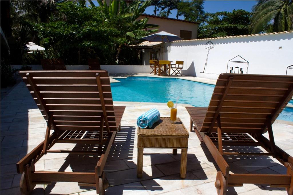 2 sillas y una mesa junto a la piscina en Pousada do Tesouro, en Paraty