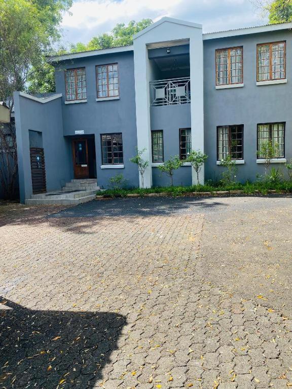 a large blue house with a brick driveway in front of it at Boutique at milner guesthouse in Bloemfontein