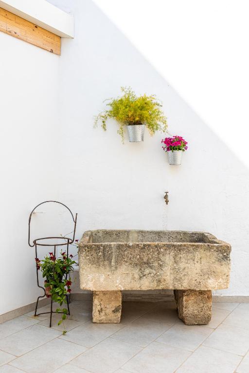 a stone bench with two potted plants on a wall at Cortile Carducci in Racale