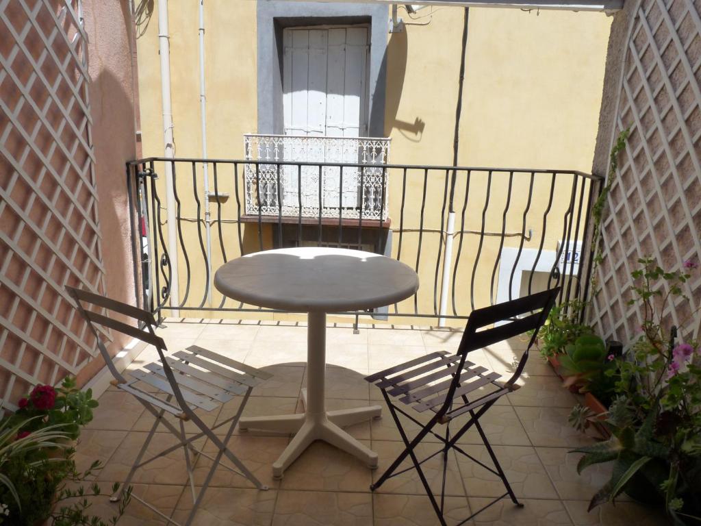 une table et deux chaises sur un balcon dans l'établissement Maison de charme - proche toutes commodités, à Marseillan