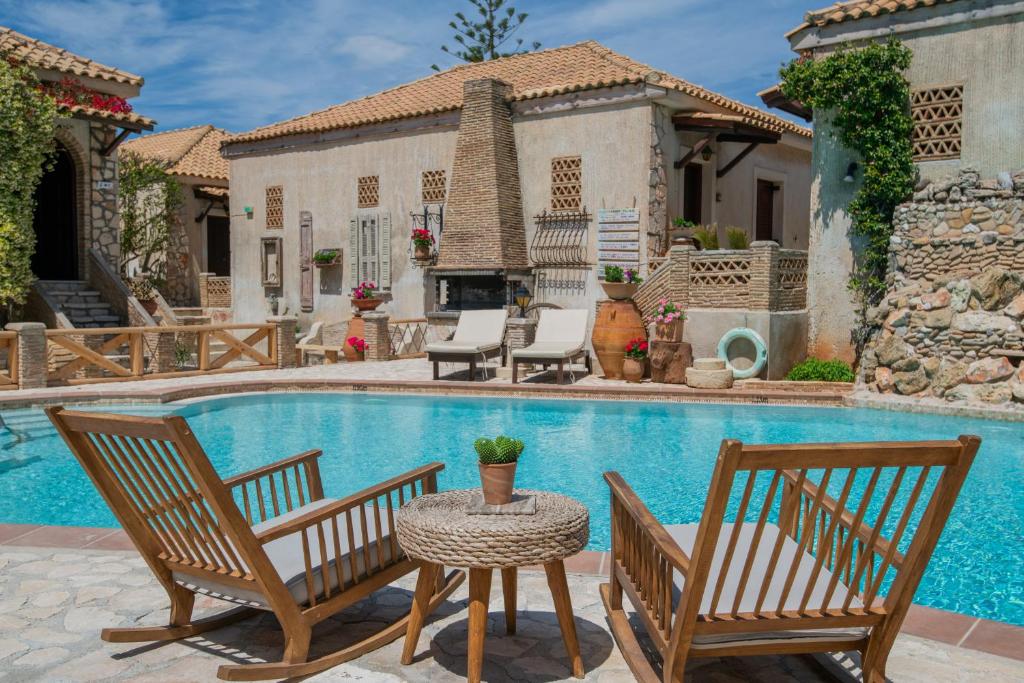 a house with a swimming pool with two chairs and a table at Garden Village Residence in Kalamaki