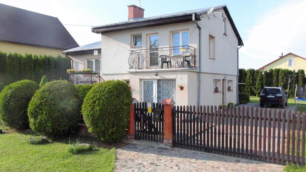 a white house with a fence in front of it at Pokoje Żabi Staw in Mikołajki