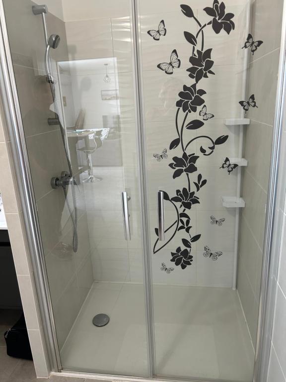 a shower with a glass door with butterflies on it at T2 500m de la plage Clim wifi parking privé in Leucate-Plage