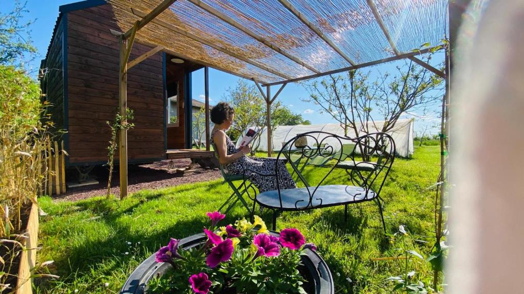 Les RosiersにあるSIMPLES ESCALES nuit en Tiny Houseの庭のテーブルに座る女