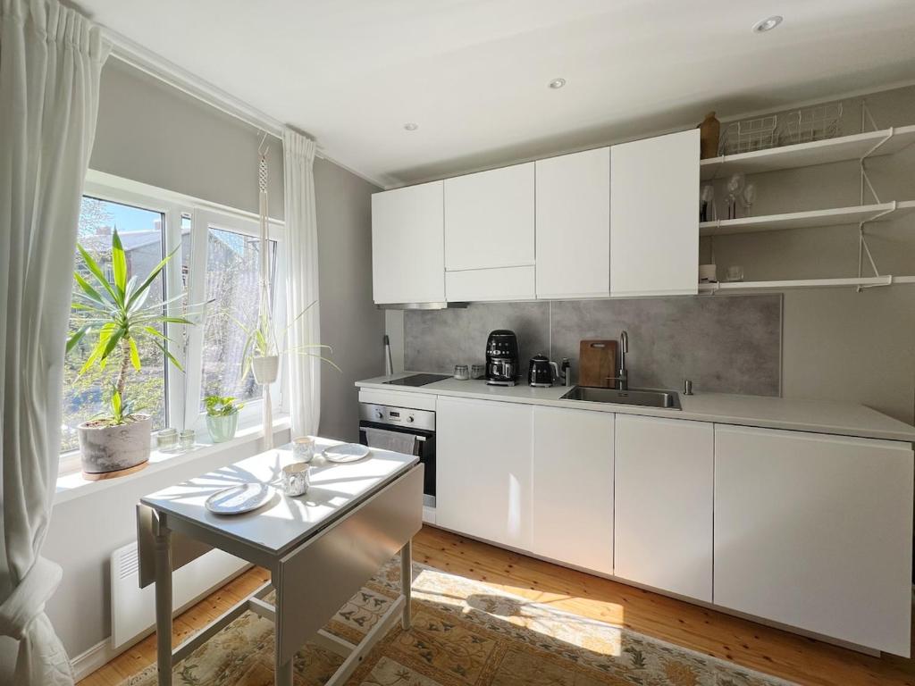 cocina con armarios blancos, mesa y ventana en Flat in Telliskivi area, en Tallin