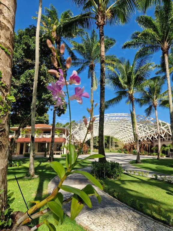a flower in front of a resort with palm trees at Pousada Vila da Barra in Ilha de Boipeba