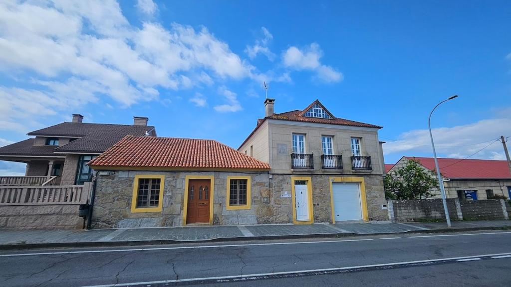 ein altes Haus am Straßenrand in der Unterkunft Casa con encanto amplios jardines al lado de la playa in Caleiro