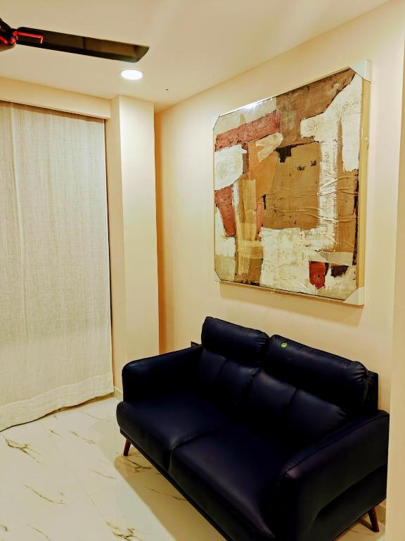 a black leather couch in a living room with a painting at Olive Retreat in Guwahati