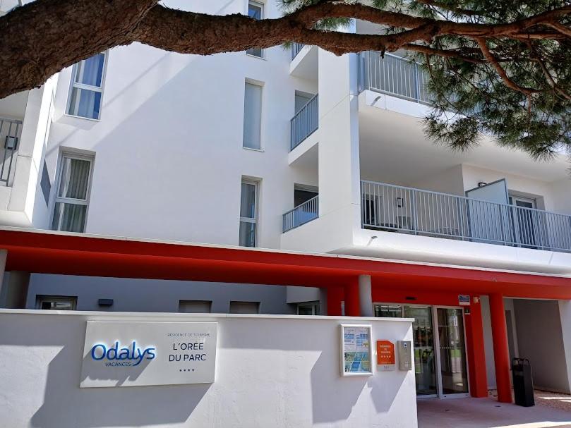 un bâtiment blanc avec un panneau devant dans l'établissement T3 avec Piscine, 150m de l'océan, à Royan