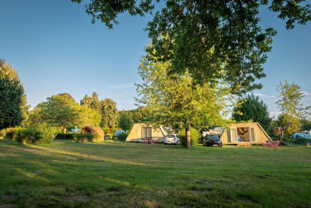 a group of tents in a field with a tree at Camping Onlycamp La Potinière in Écueillé