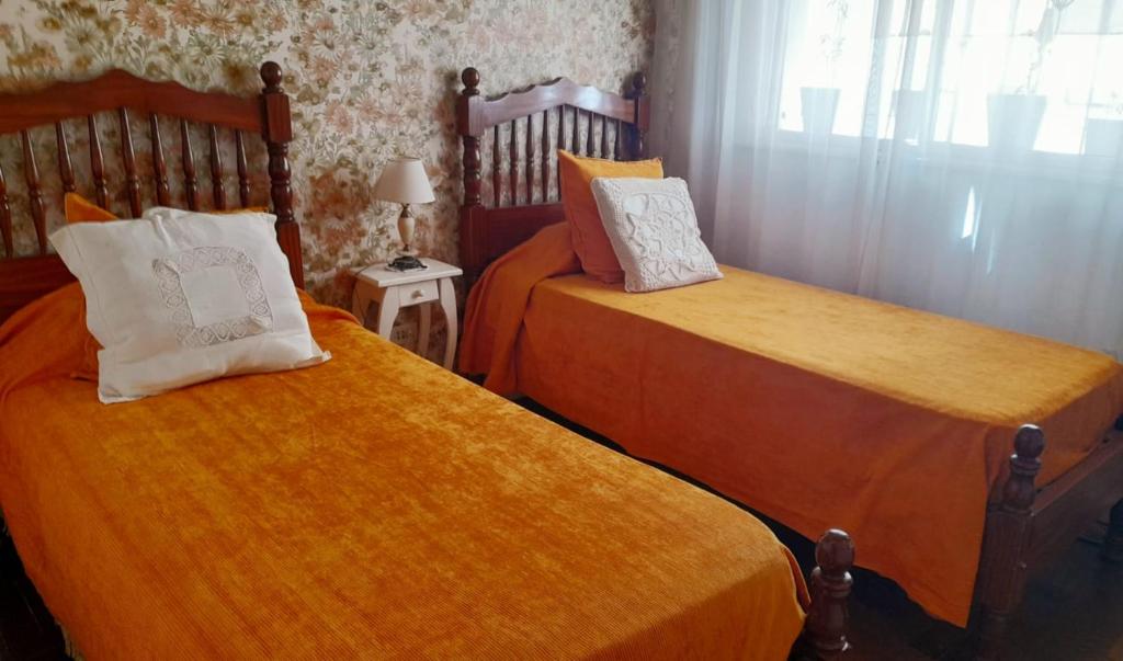 Un dormitorio con dos camas con sábanas naranjas. en Dpto Nenucha, en Bahía Blanca